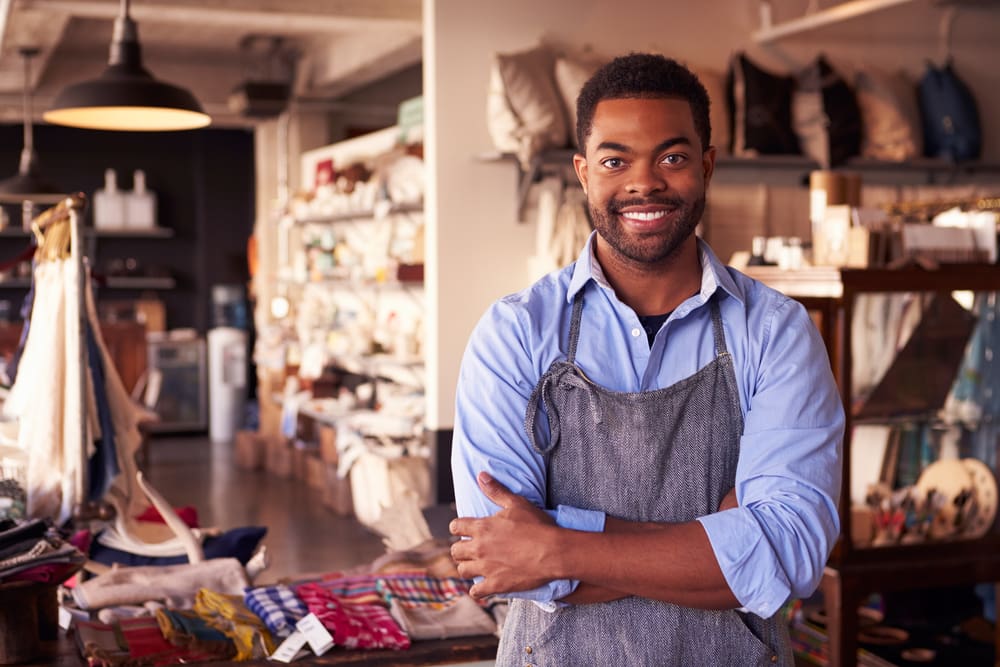 Proud business owner stands smiling in his small shop