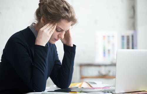 A stressed woman worries while looking at her computer