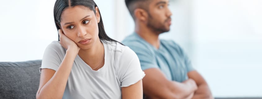 Shot of a young couple sitting on the sofa at home and ignoring each other after a fight