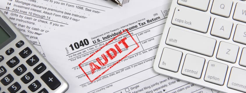 IRS & EDD AUDITS Concept image for filing federal income taxes online and being audited. Computer keyboard, calculator and pen are placed on income tax form 1040. The 'word' AUDIT is stamped on the form 1040.