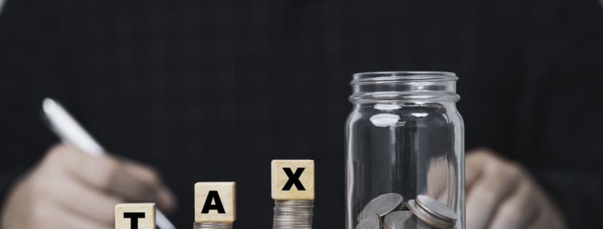 Accountants make accounts, income, expenses, annually to calculate taxation with coins stacking and saving jar for tax reduce and refund concept.