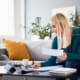 Smiling woman analysing bills filling tax documents while at sitting on sofa at home