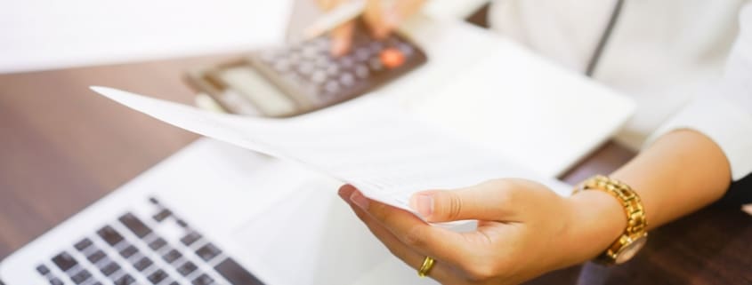 Woman holding a paper and a calculator