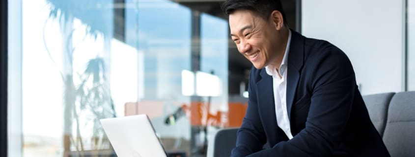 Man smiling while using a laptop